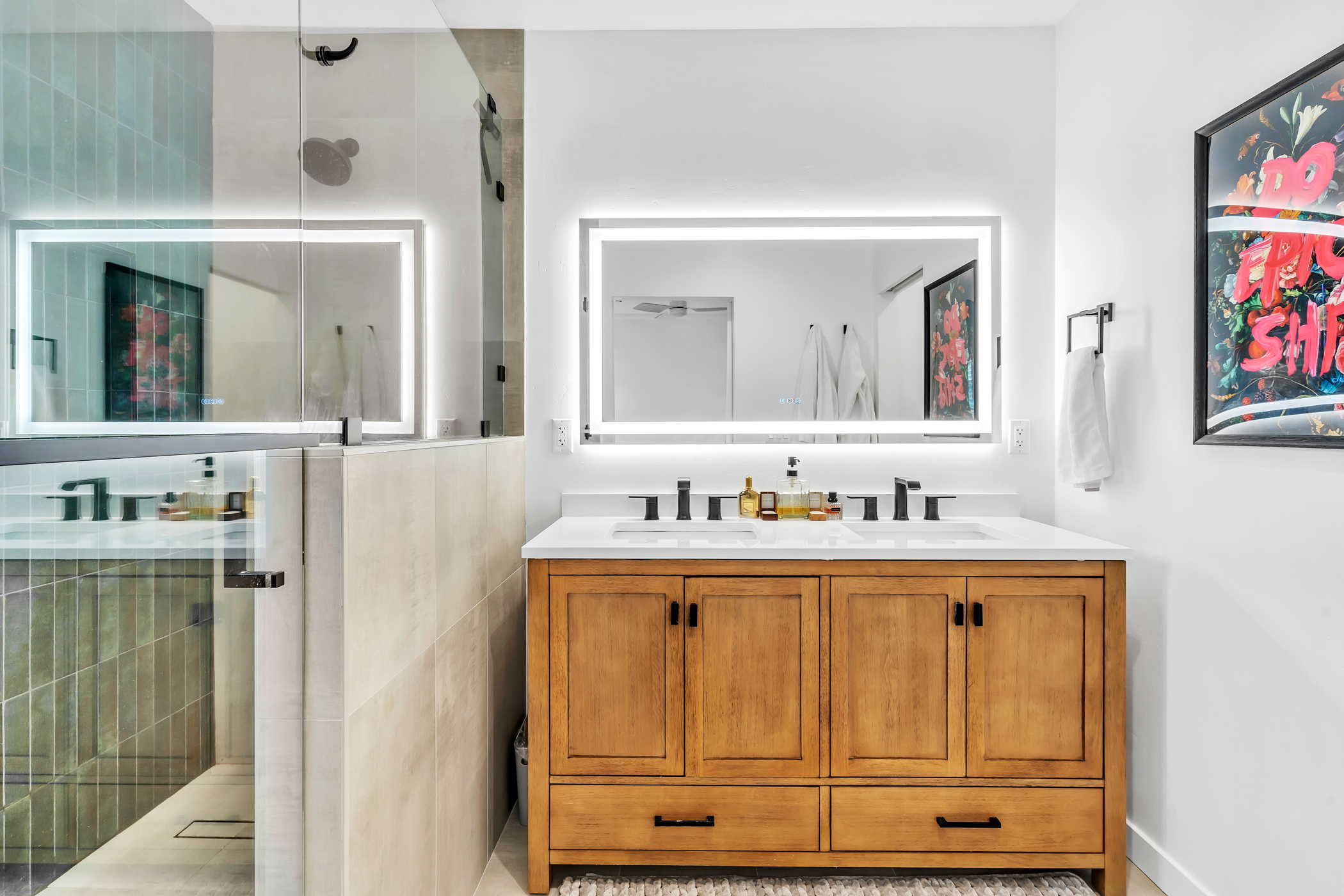 Modern primary bathroom on main level featuring a double vanity with wood cabinetry, backlit mirror, and walk-in glass shower at 2146 Franklin Avenue in Logan Heights. Listed by Portia Green, REALTOR® at Compass in San Diego.