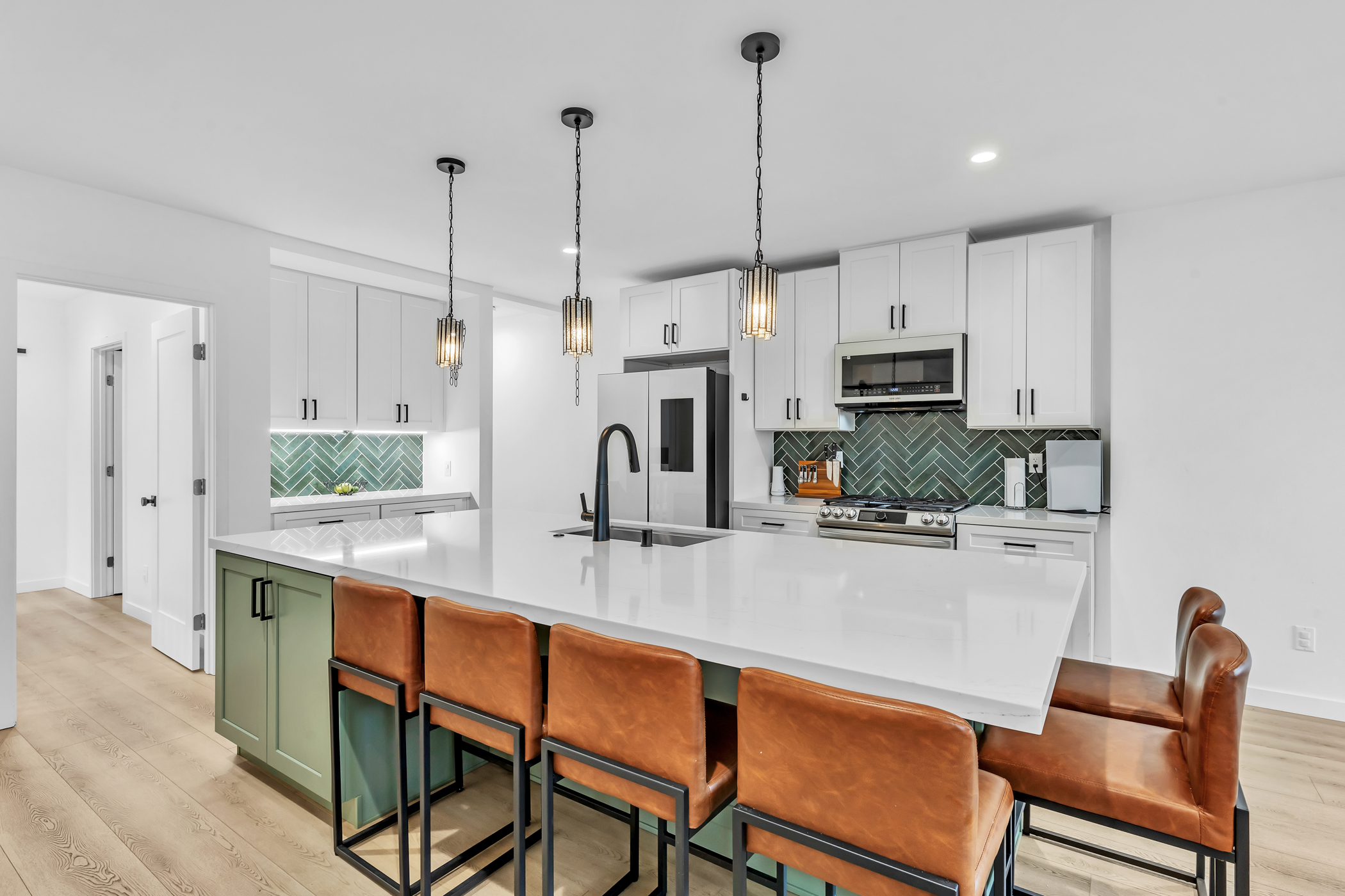 Bright modern kitchen with oversized quartz island, green herringbone backsplash, and leather bar seating at 2146 Franklin Avenue in Logan Heights. Listed by Portia Green, REALTOR® at Compass in San Diego.