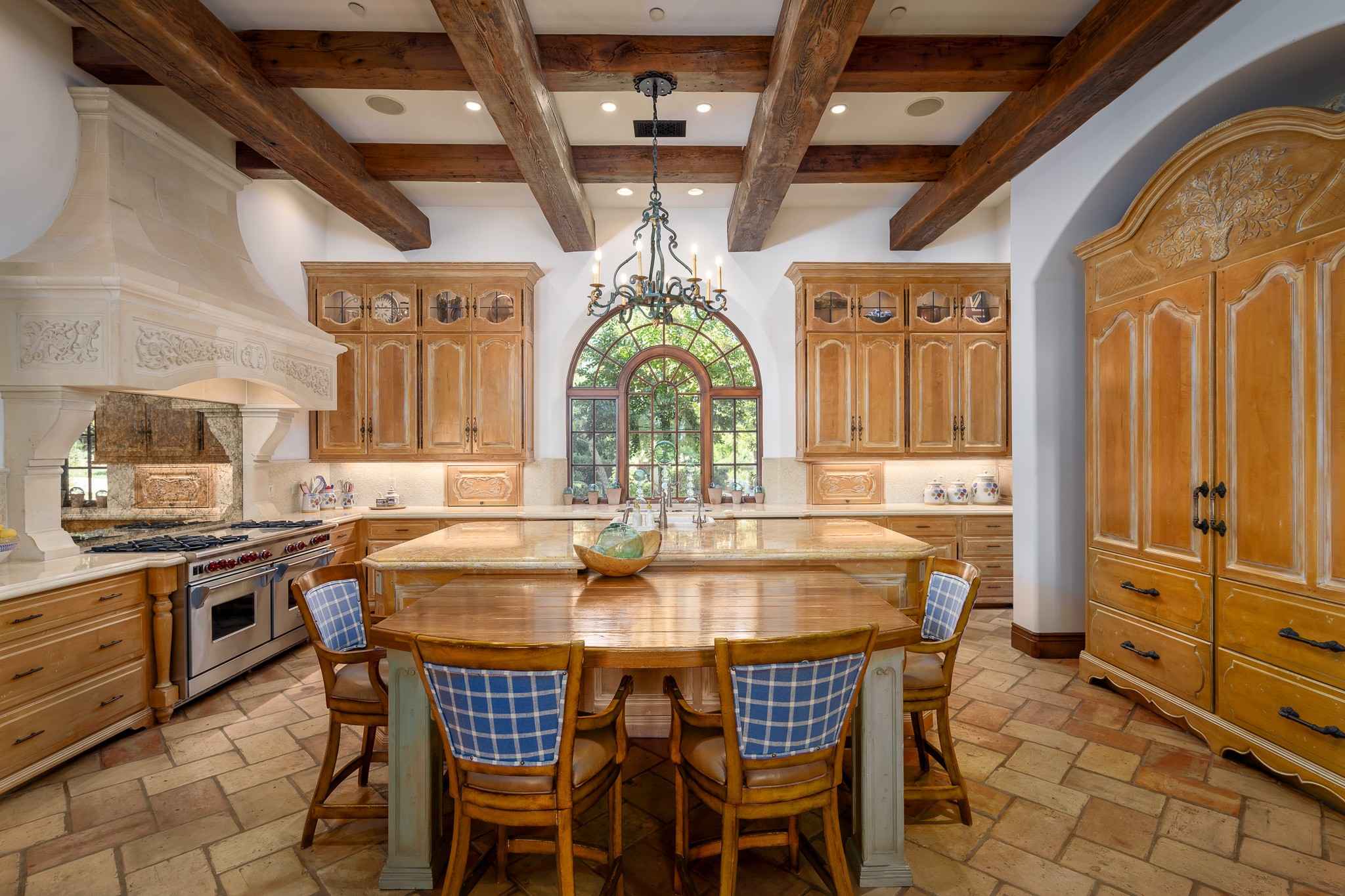 Remodeled Rancho Santa Fe kitchen with exposed wood beams, arched window, and custom cabinetry blending rustic charm and modern design